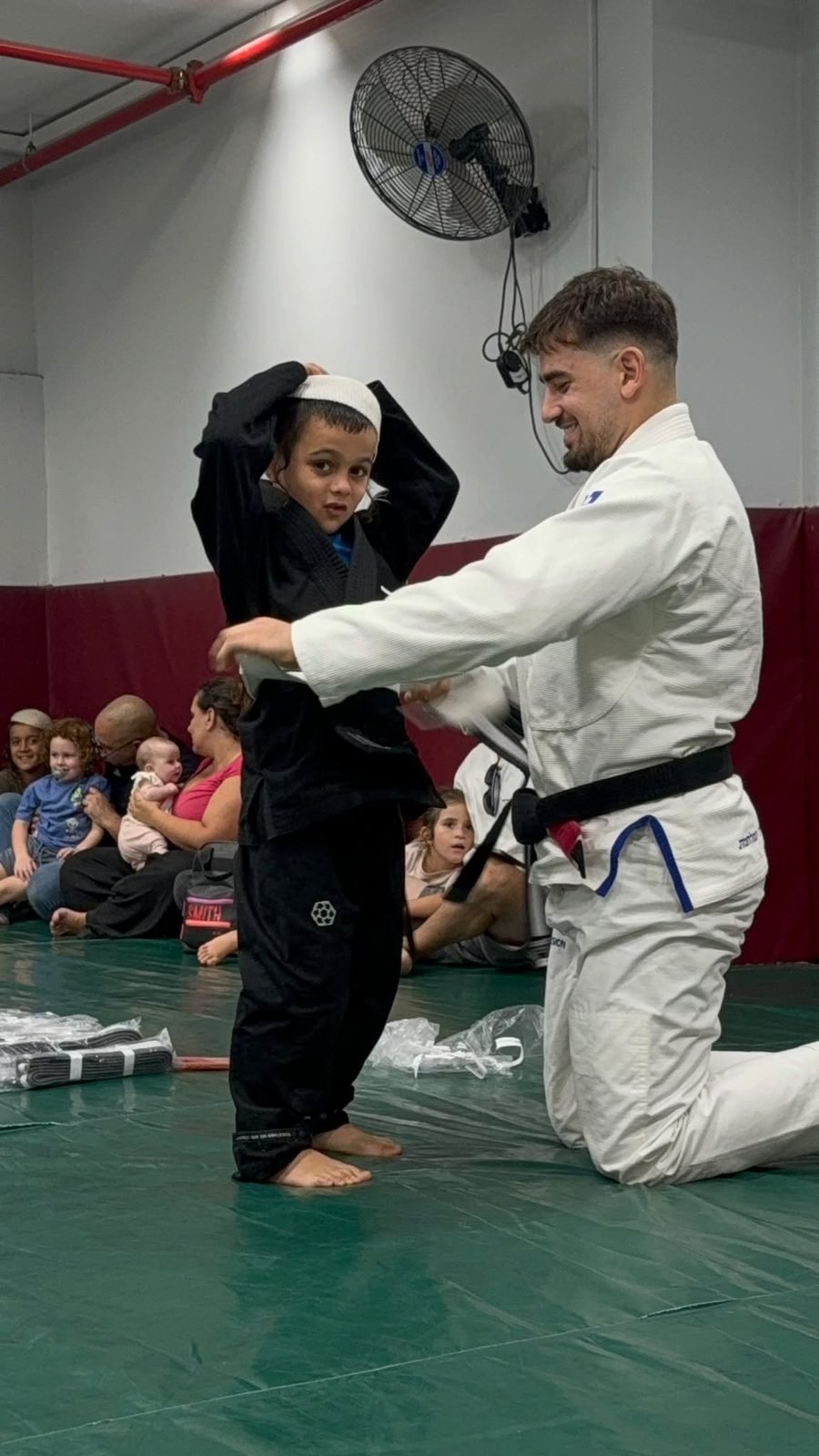 שלו אלנברג קושר חגורה למתאמן צעיר ב-Fusion BJJ חיפה