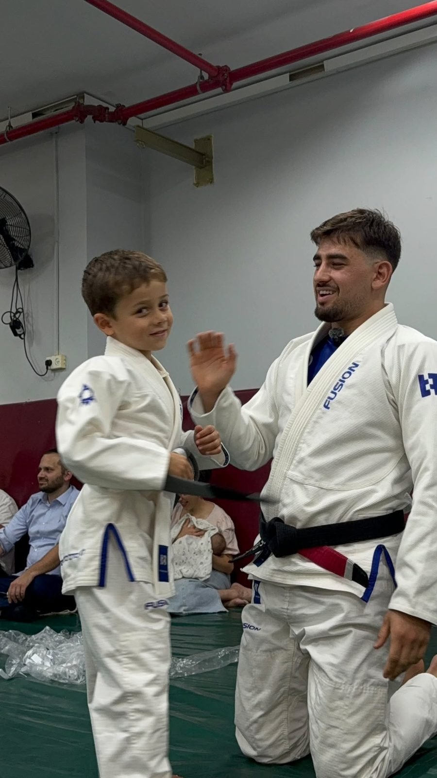 שלו אלנברג נותן כיף למתאמן צעיר בטקס החגורות ב-Fusion BJJ
