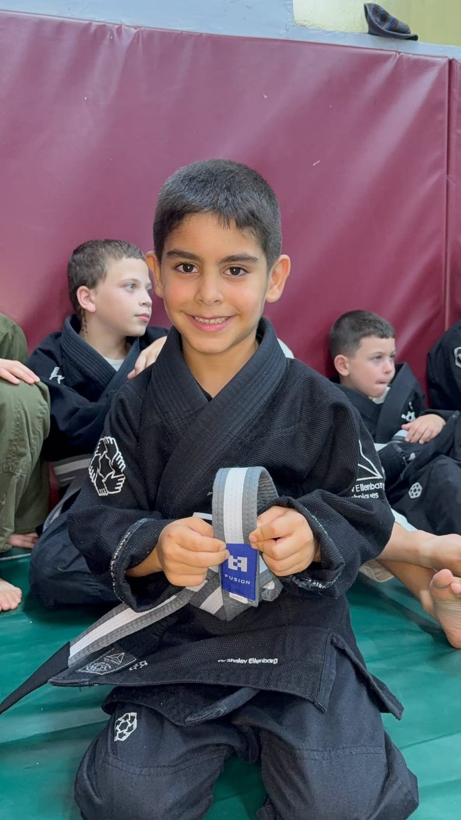 ילד ב-Fusion BJJ חיפה מחזיק את החגורה החדשה שקיבל בטקס