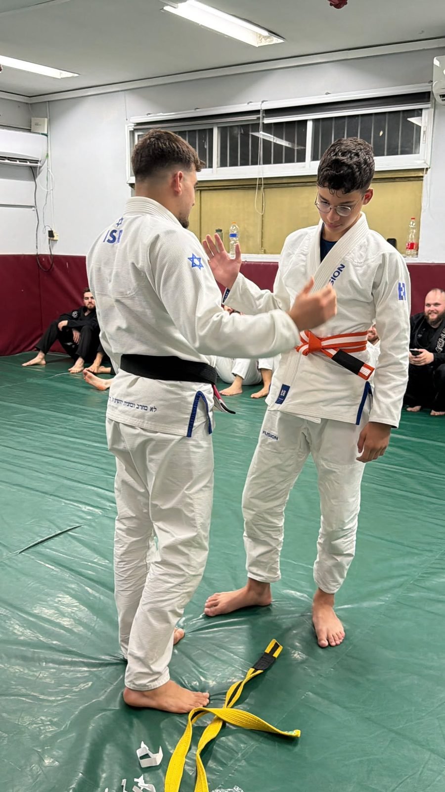מתאמן נוער מקבל חגורה כתומה בטקס Fusion BJJ חיפה